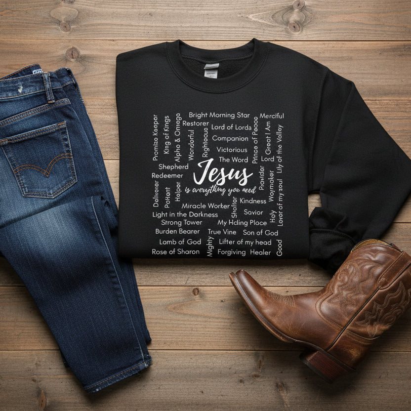 black sweatshirt with white text on wood background with jeans and cowboy boot sitting near by