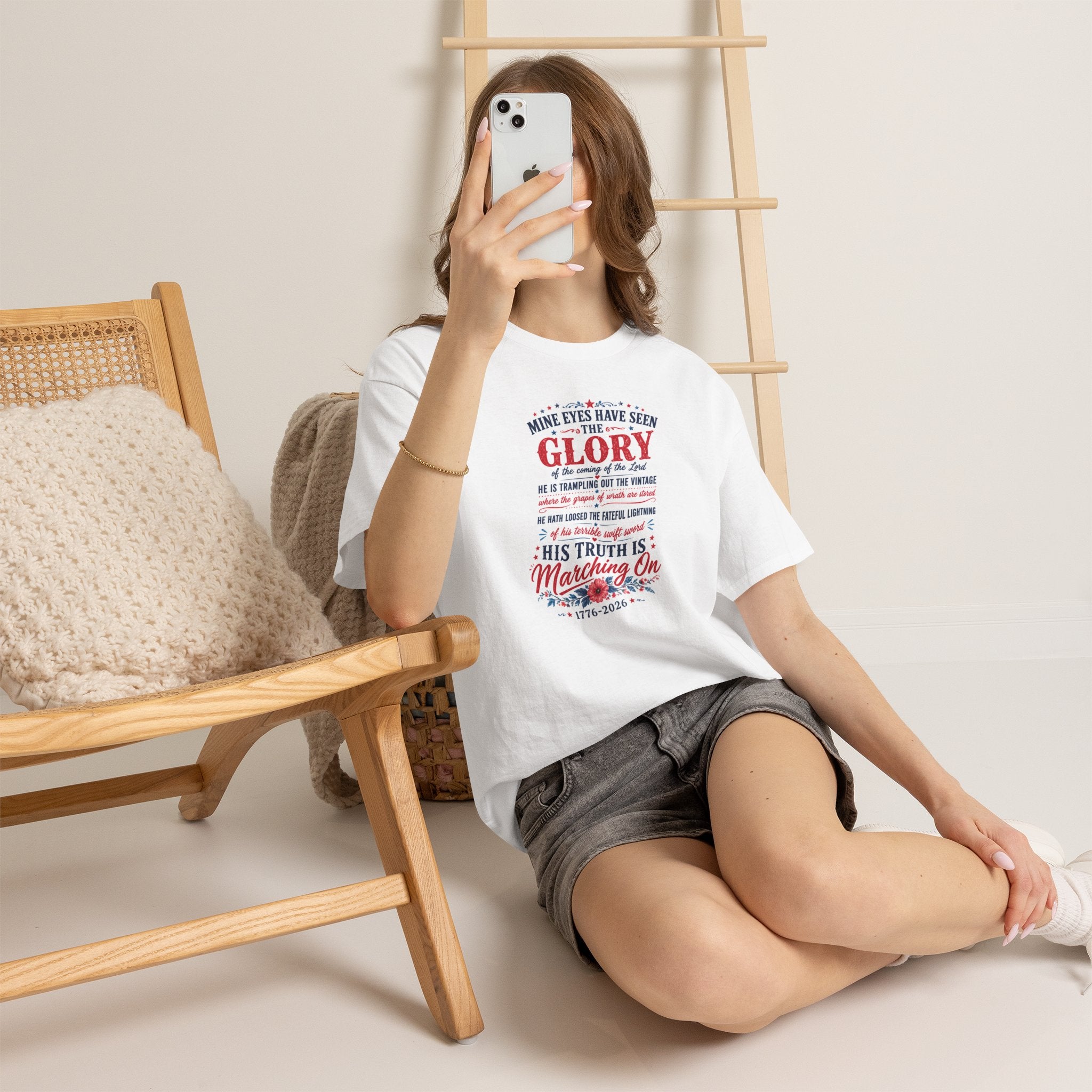 Woman sitting on the floor holding a phone, wearing a white t-shirt with a black dancer design.