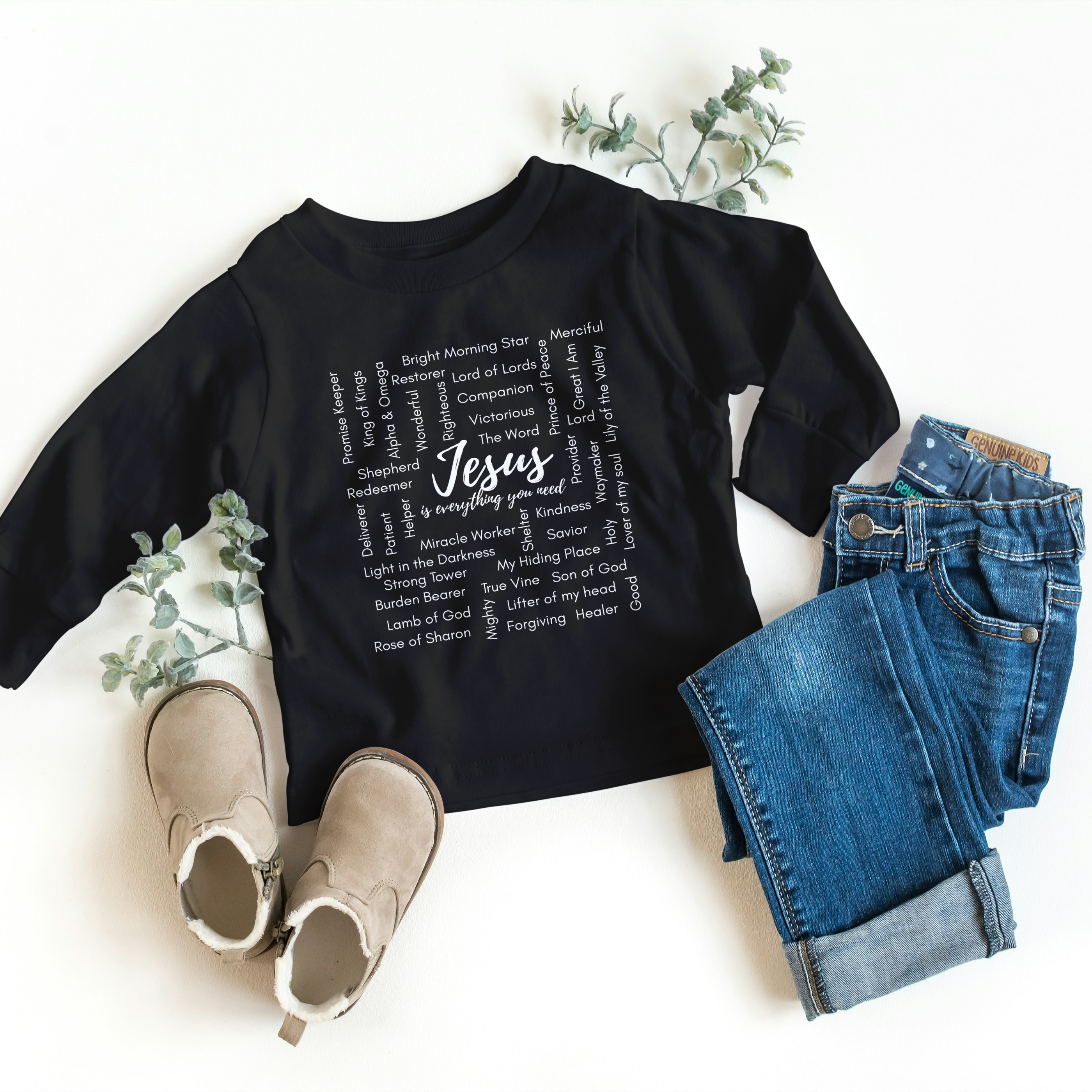Black t-shirt with 'Jesus' text, paired with jeans and shoes on a white background